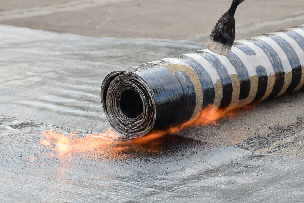 Roofing installation felt with heating and melting bitumen roll by torch on flame, closeup detail shoot.